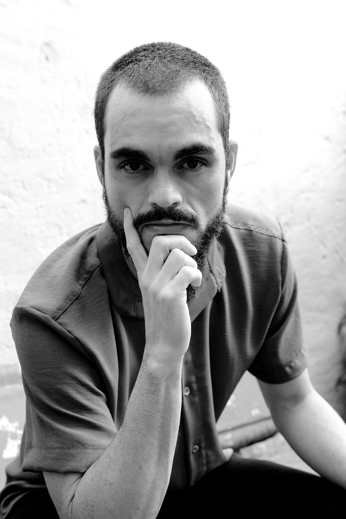 Retrato em preto e branco de Jean Prestes, com a mão no queixo